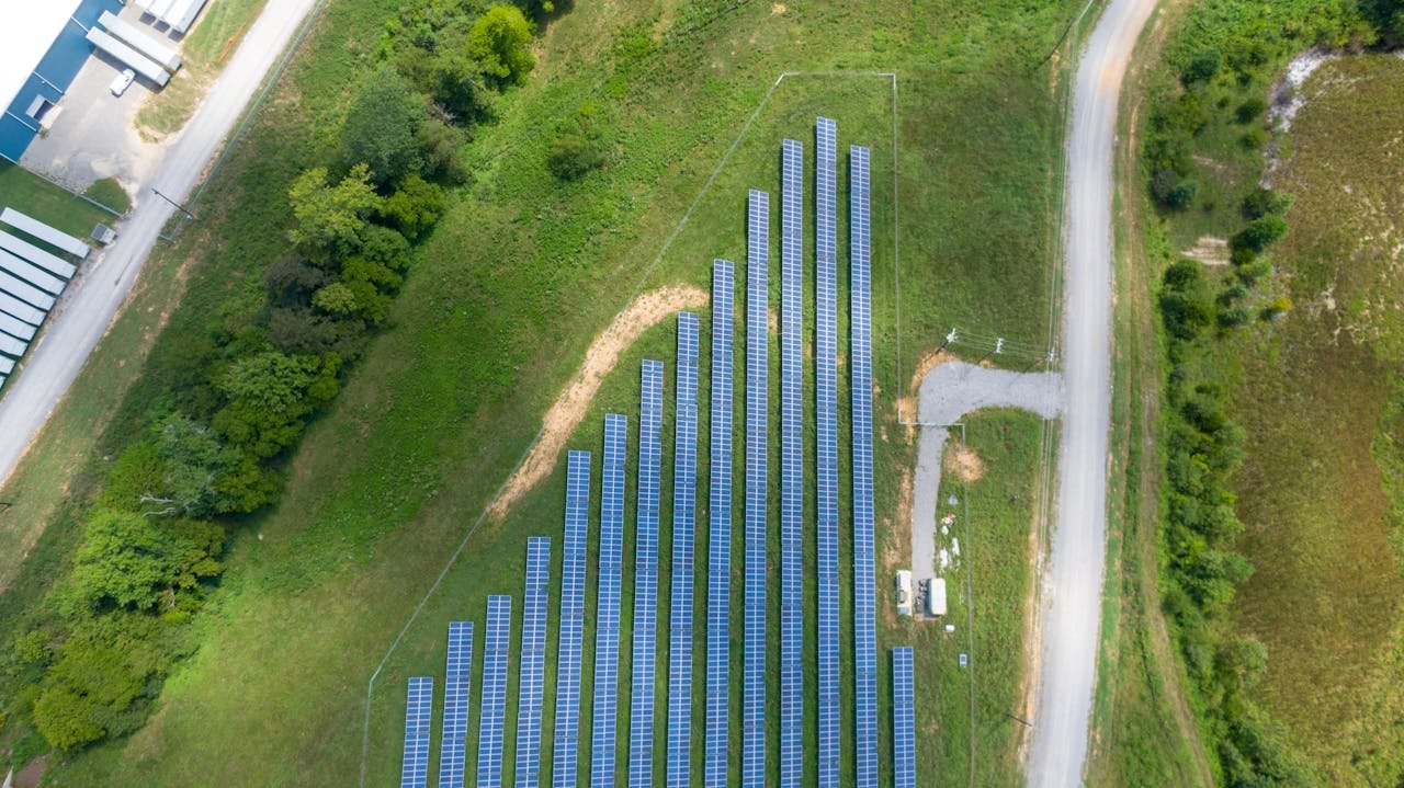 services-02 Aerial view showing a solar panel array in a lush rural landscape with a road.