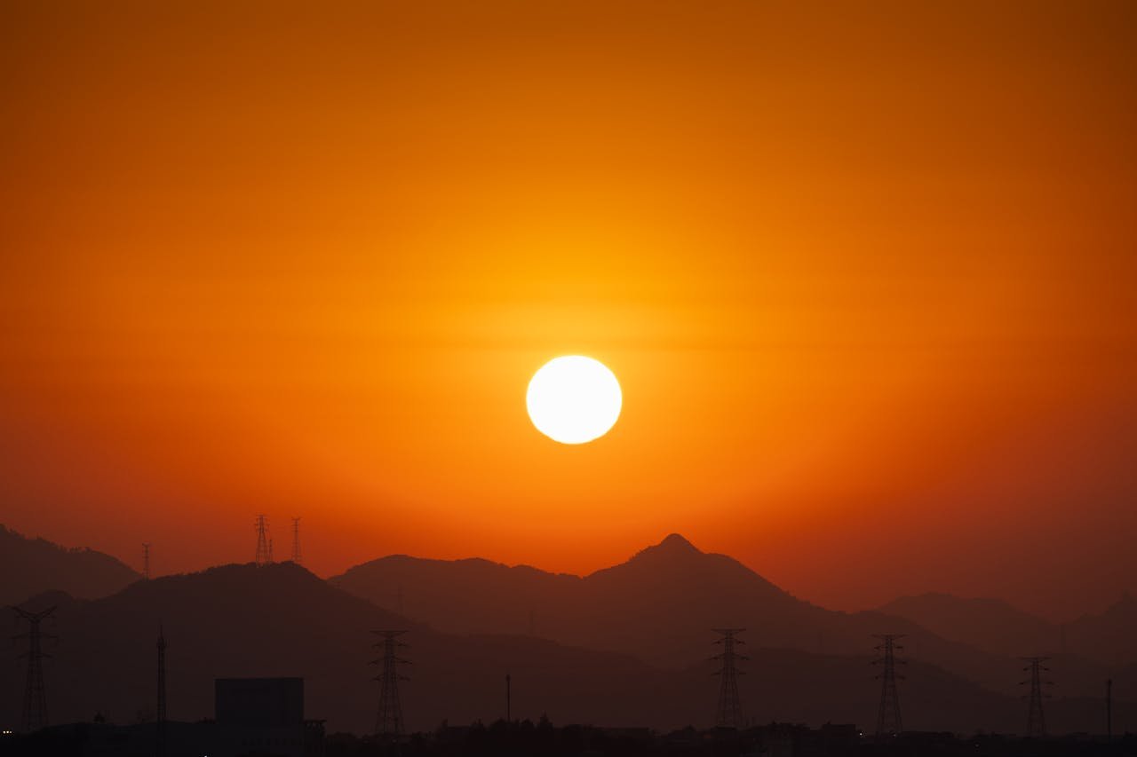 about-05 Captivating sunset with mountains and electrical towers silhouetted against an orange sky.