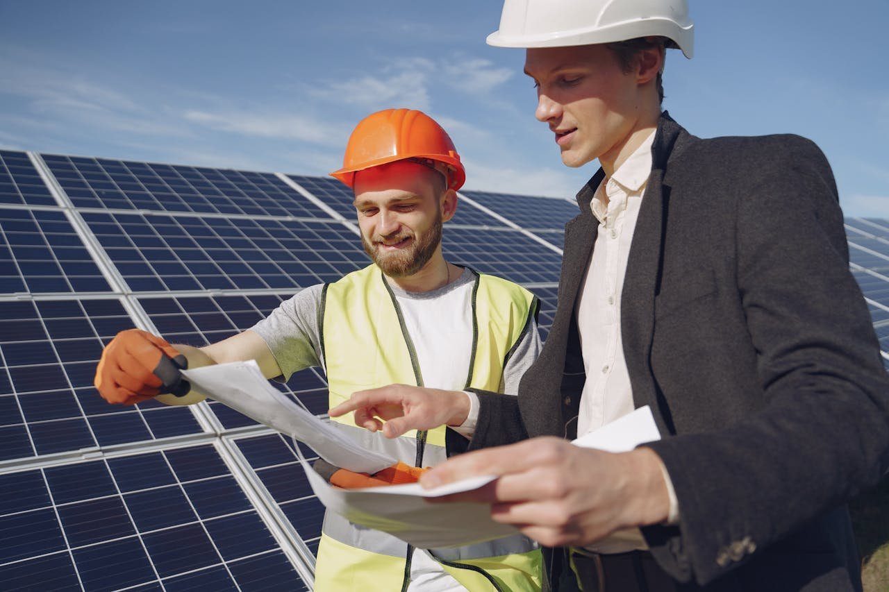 services-05 Two engineers reviewing plans for solar panel installation, representing teamwork in renewable energy.
