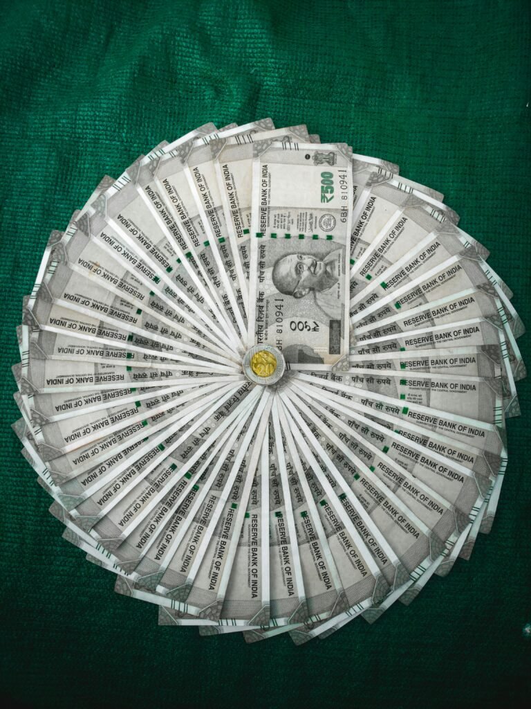 pexels photo 6484708 6484708 Top view of Indian Rupee notes arranged in a circular pattern on a green surface.